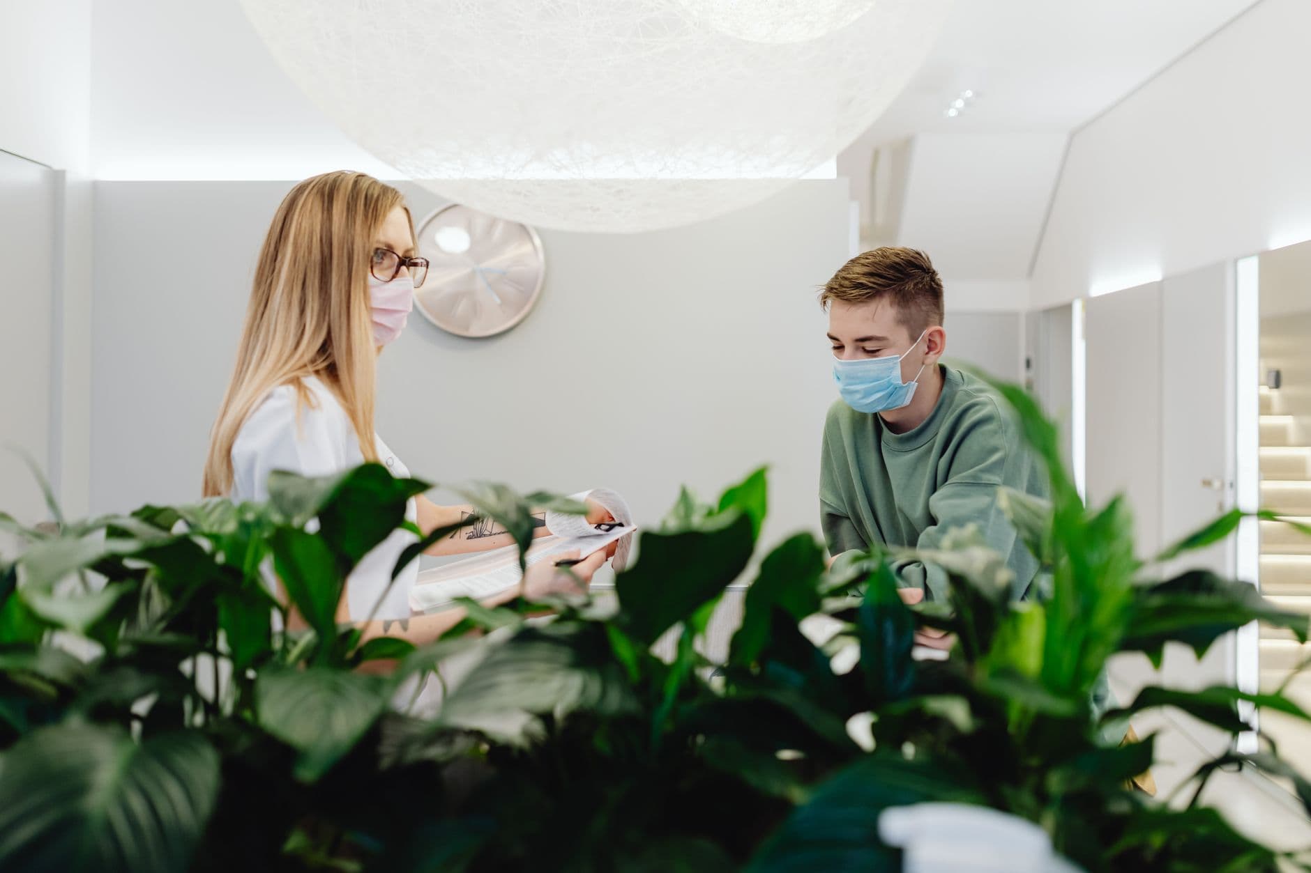 Clinic & Hospital Appointment Websites — Reception area in a healthcare facility with masked staff and patients interacting indoors.