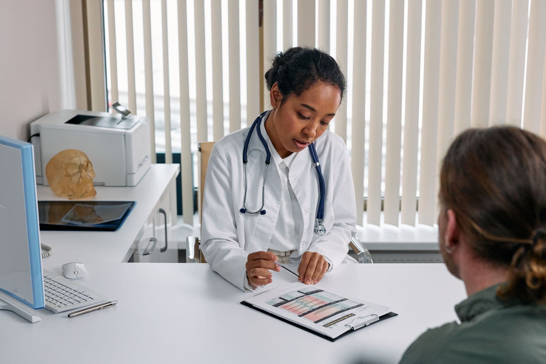 Clinic & Hospital Appointment Websites — A doctor consulting with a patient in an office, discussing a medical chart.