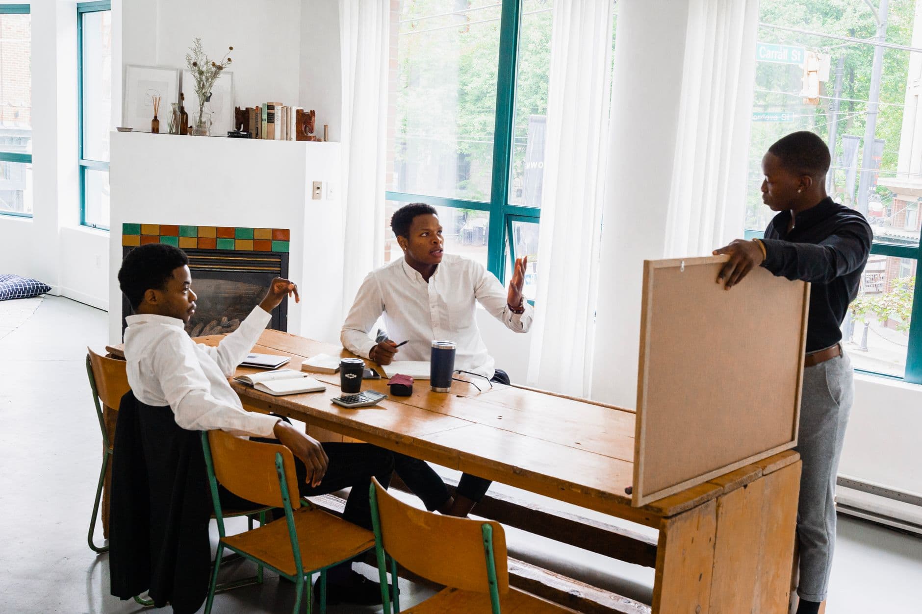 Cloud Hosting for Digital Agencies — Three men discussing a project at a table in a bright office setting.