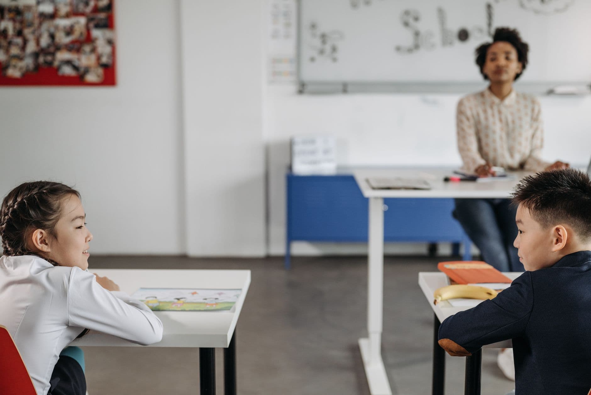 Coaching Institute Websites — Two students engage in a classroom setting with their teacher in the background.