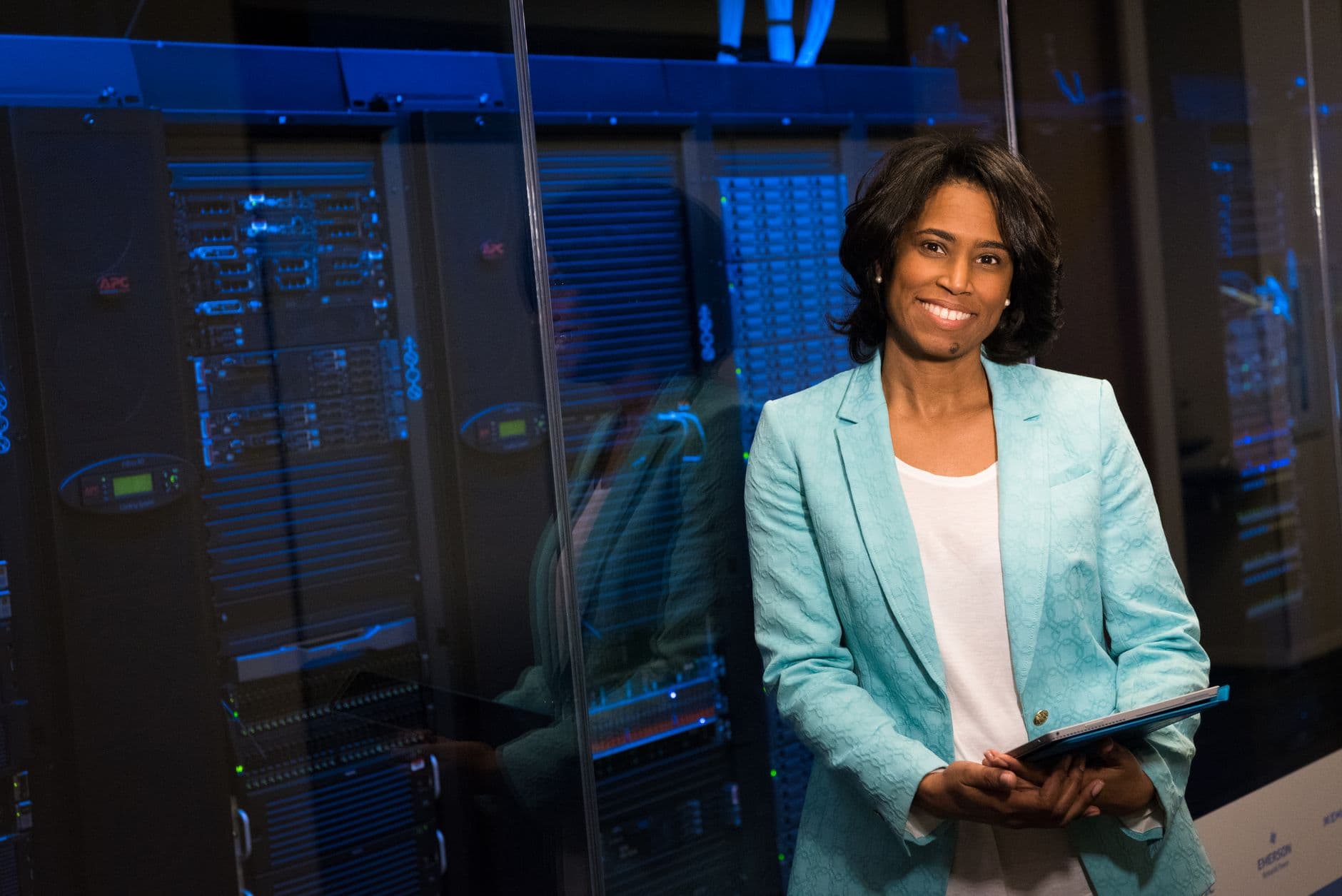Dedicated Servers for SaaS Companies — Smiling woman in data center showcasing technology expertise.