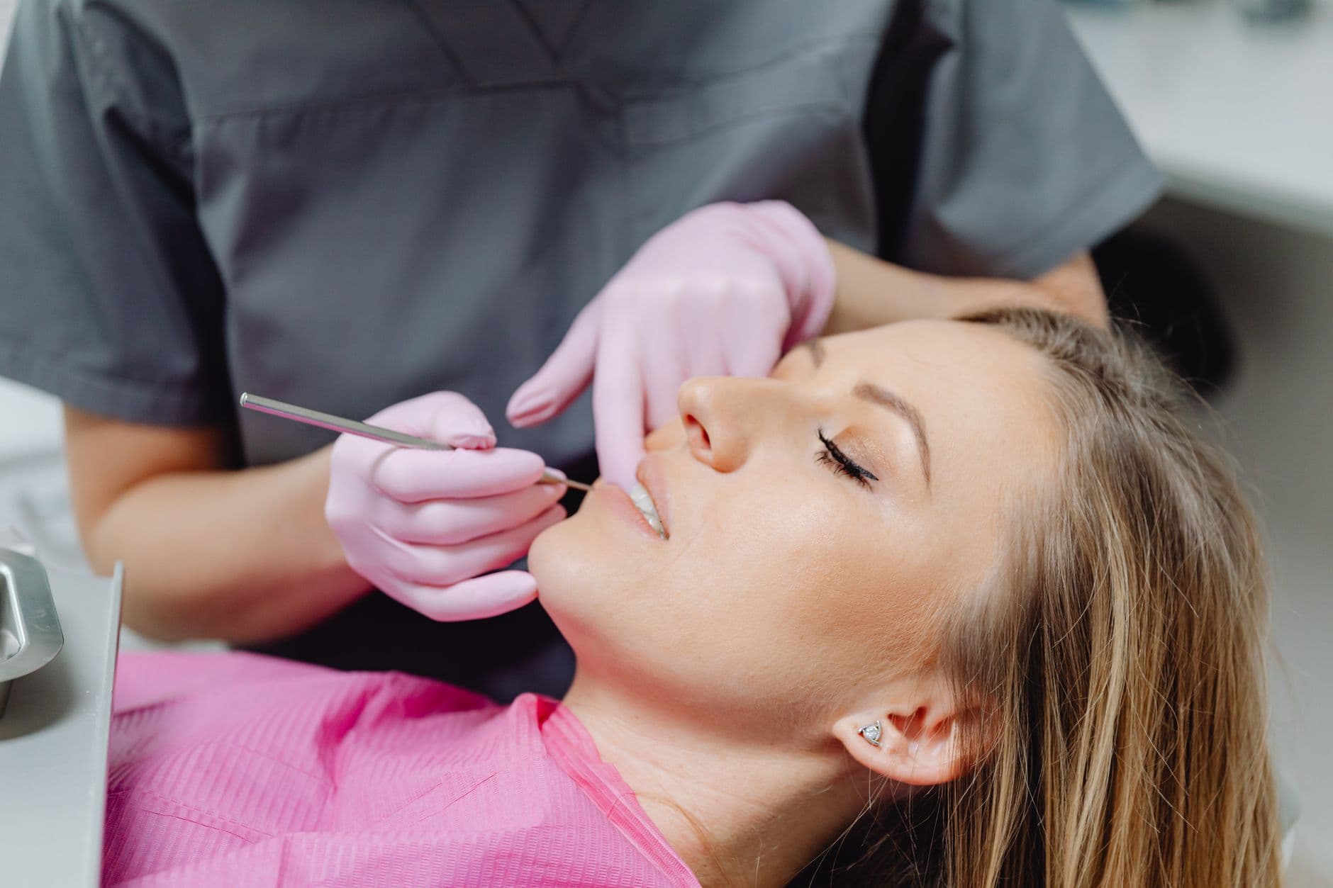 Dentist Appointment Websites — A female patient receives a dental examination by a dentist in a clinic.