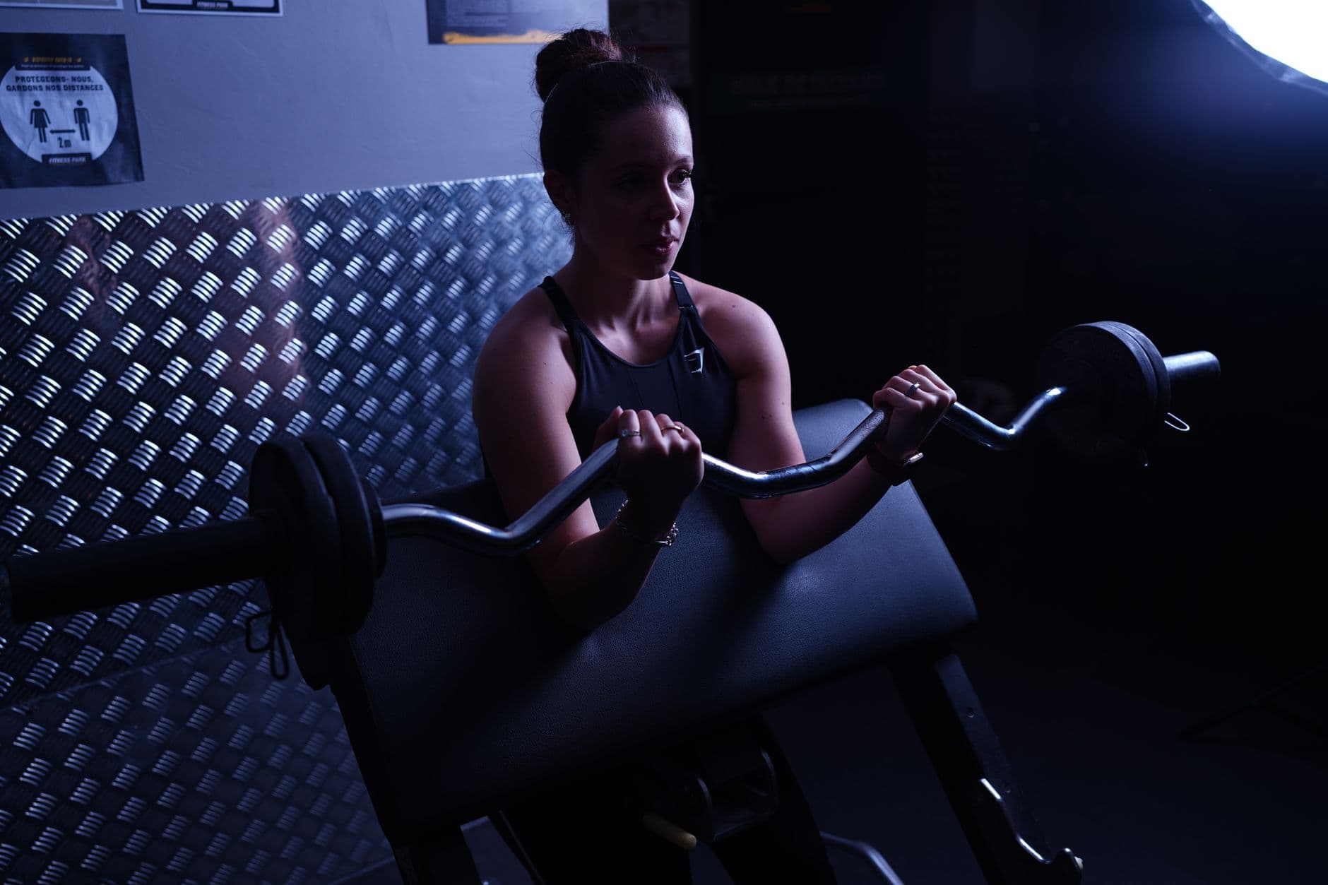 Gym & Fitness Websites — Focused woman weightlifting with barbell in a Paris gym, highlighting strength and determination.