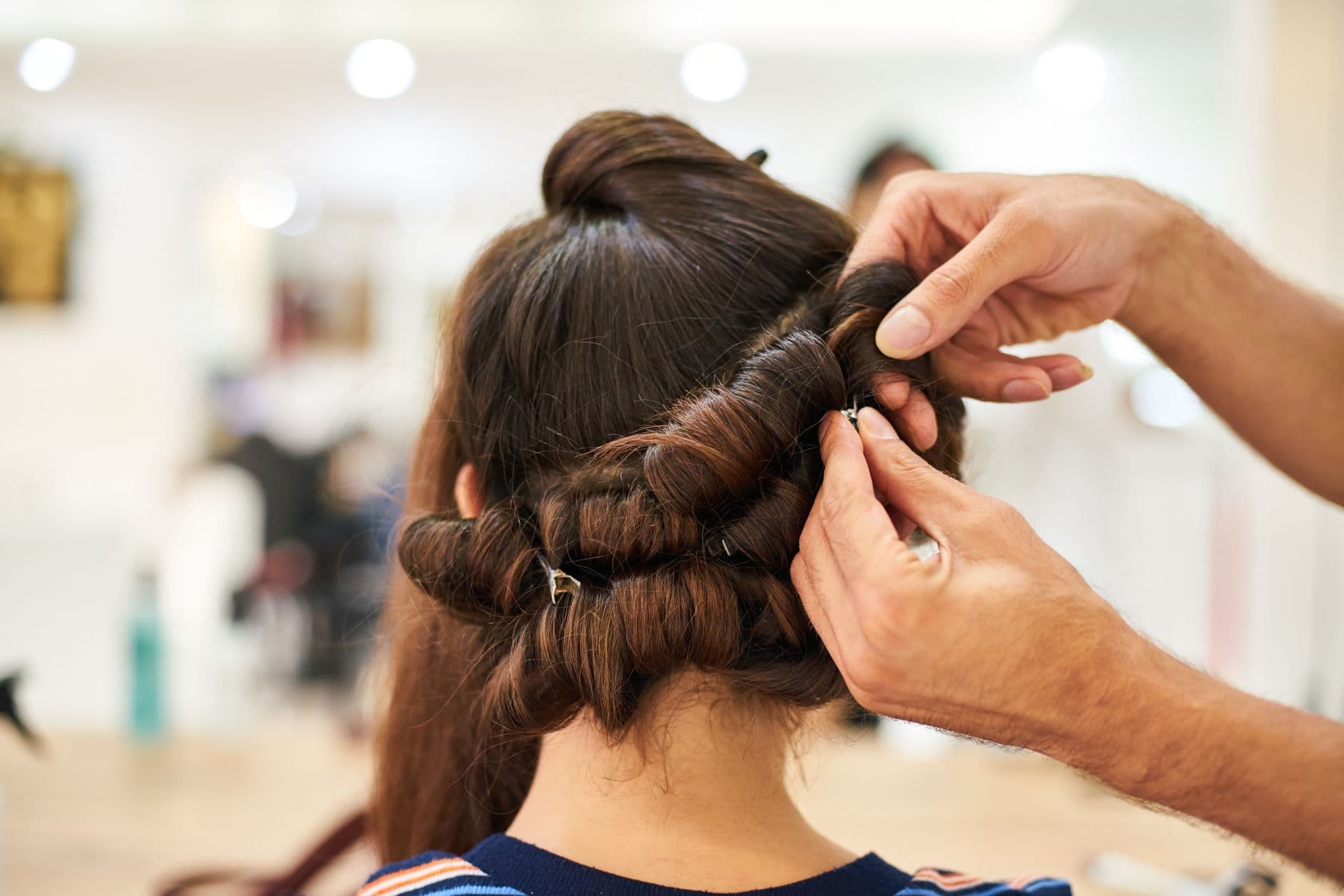 Salon Appointment Websites — Close-up of a stylist crafting an intricate updo hairstyle in a modern salon.