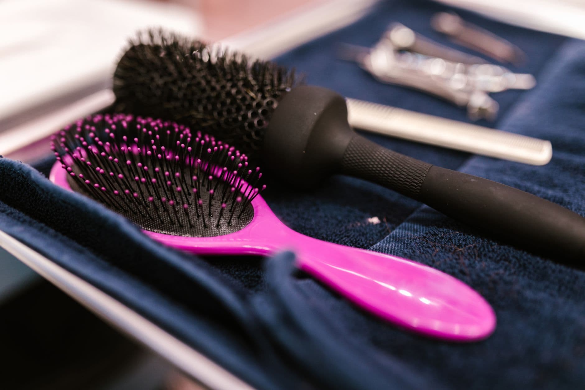 Salon Appointment Websites — Close-up of pink and black hairbrushes on a towel in a salon setting.