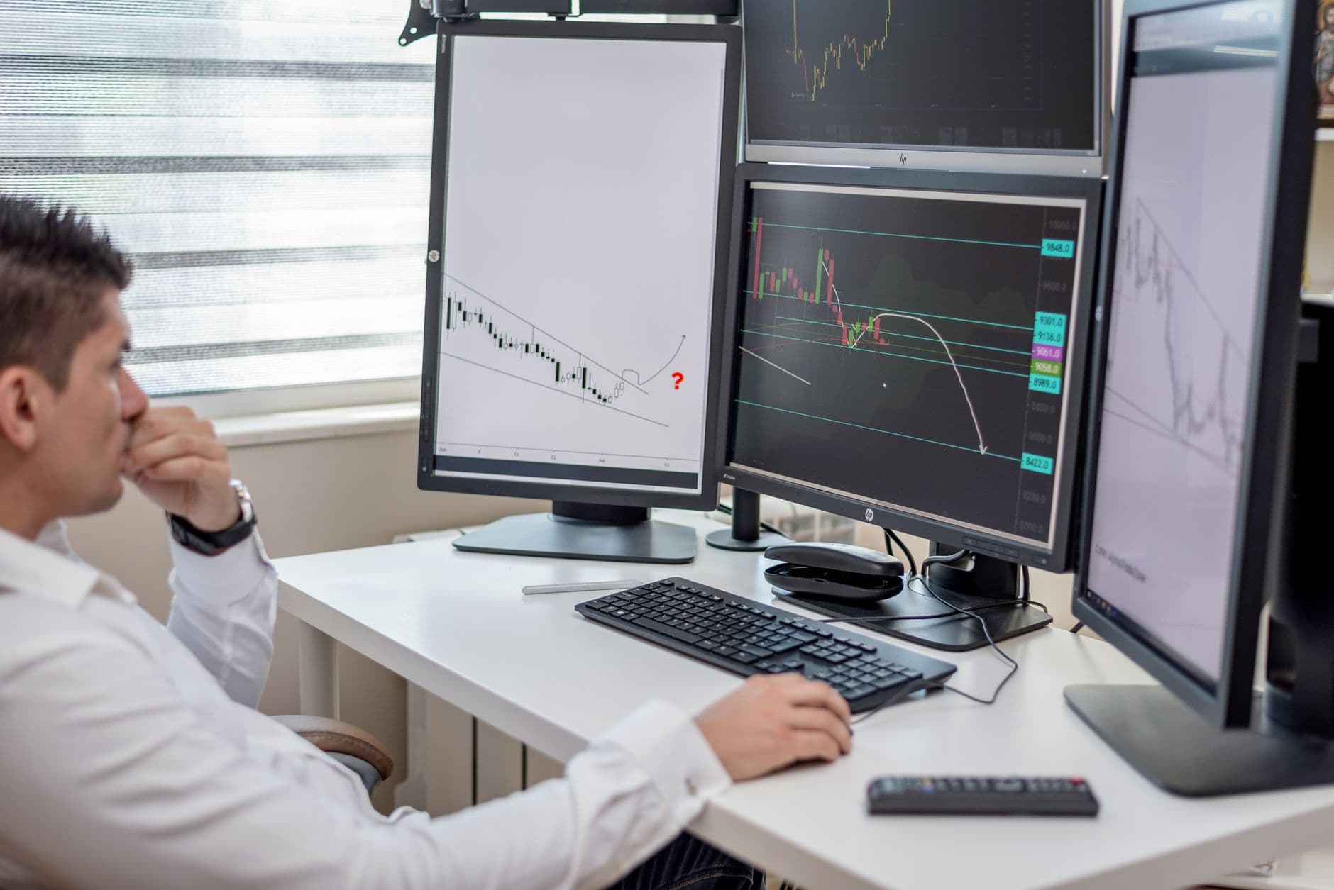 VPS Hosting for Forex Trading — Business professional analyzing financial data on multiple computer monitors at his workspace.