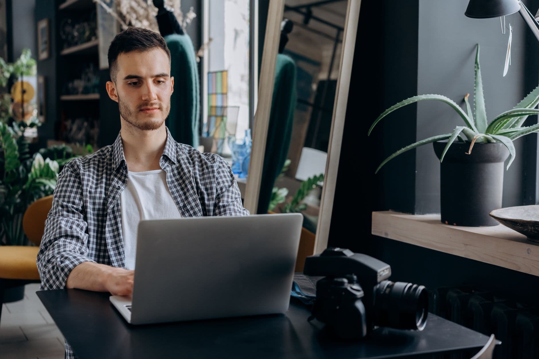 VPS Hosting for Freelancers — Man in plaid shirt working on a laptop in a modern home office setting.
