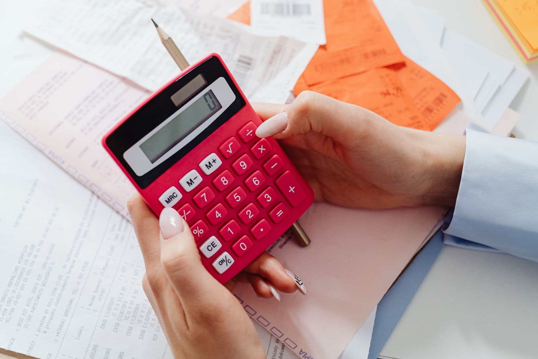 Website & Hosting for Chartered Accountants — Close-up of hands holding a red calculator, managing finances with documents and receipts.