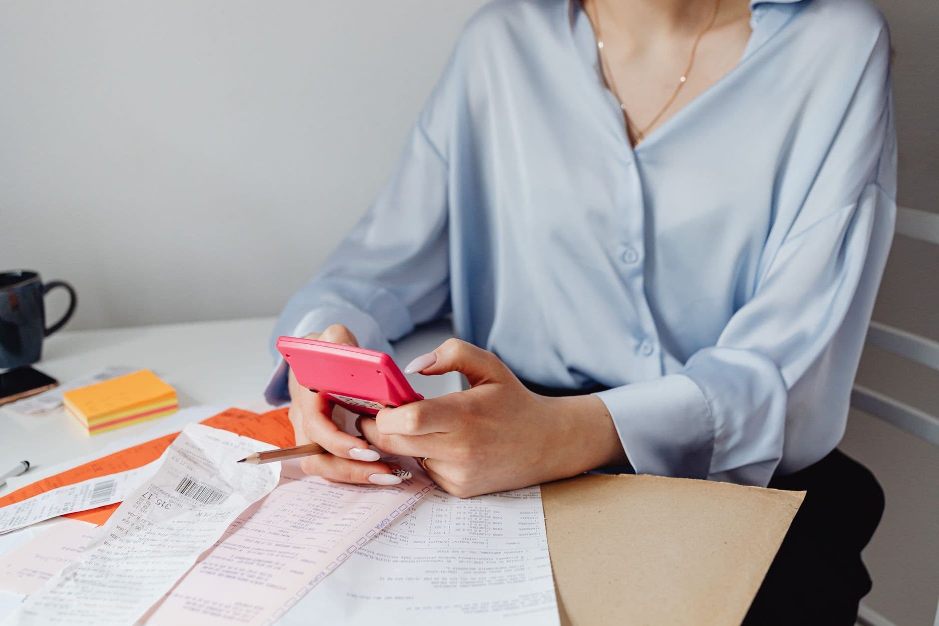 Website & Hosting for Chartered Accountants — A woman using a pink calculator surrounded by bills and receipts at a desk.