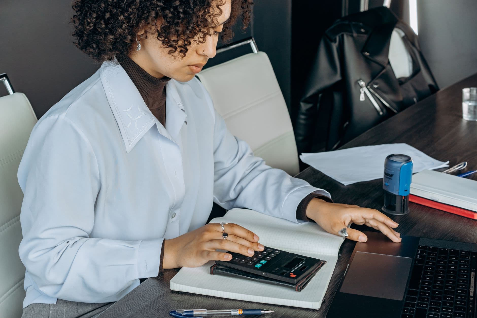 Website & Hosting for Chartered Accountants — Young woman in office using a calculator for financial calculations.