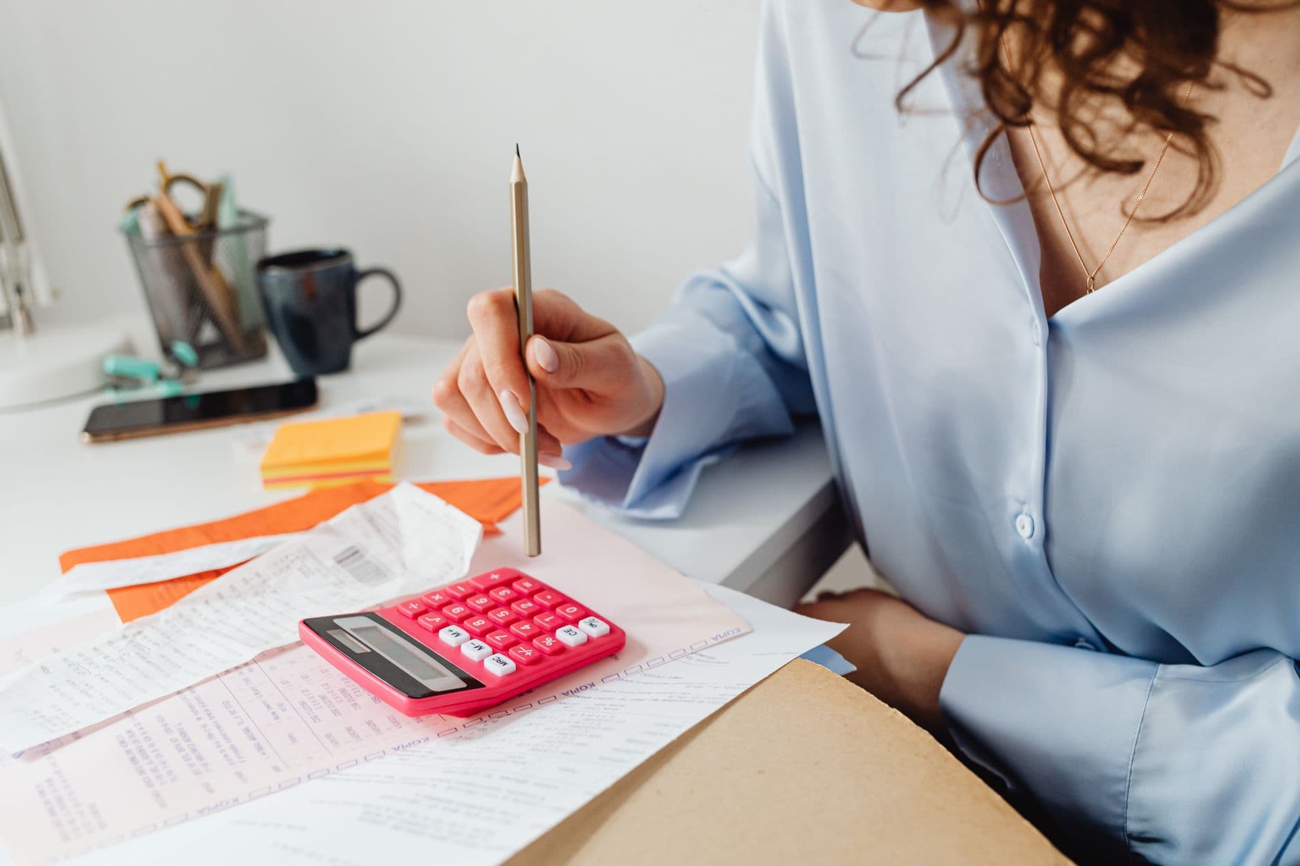 Website & Hosting for Chartered Accountants — A woman is calculating expenses using a calculator and papers at her desk.