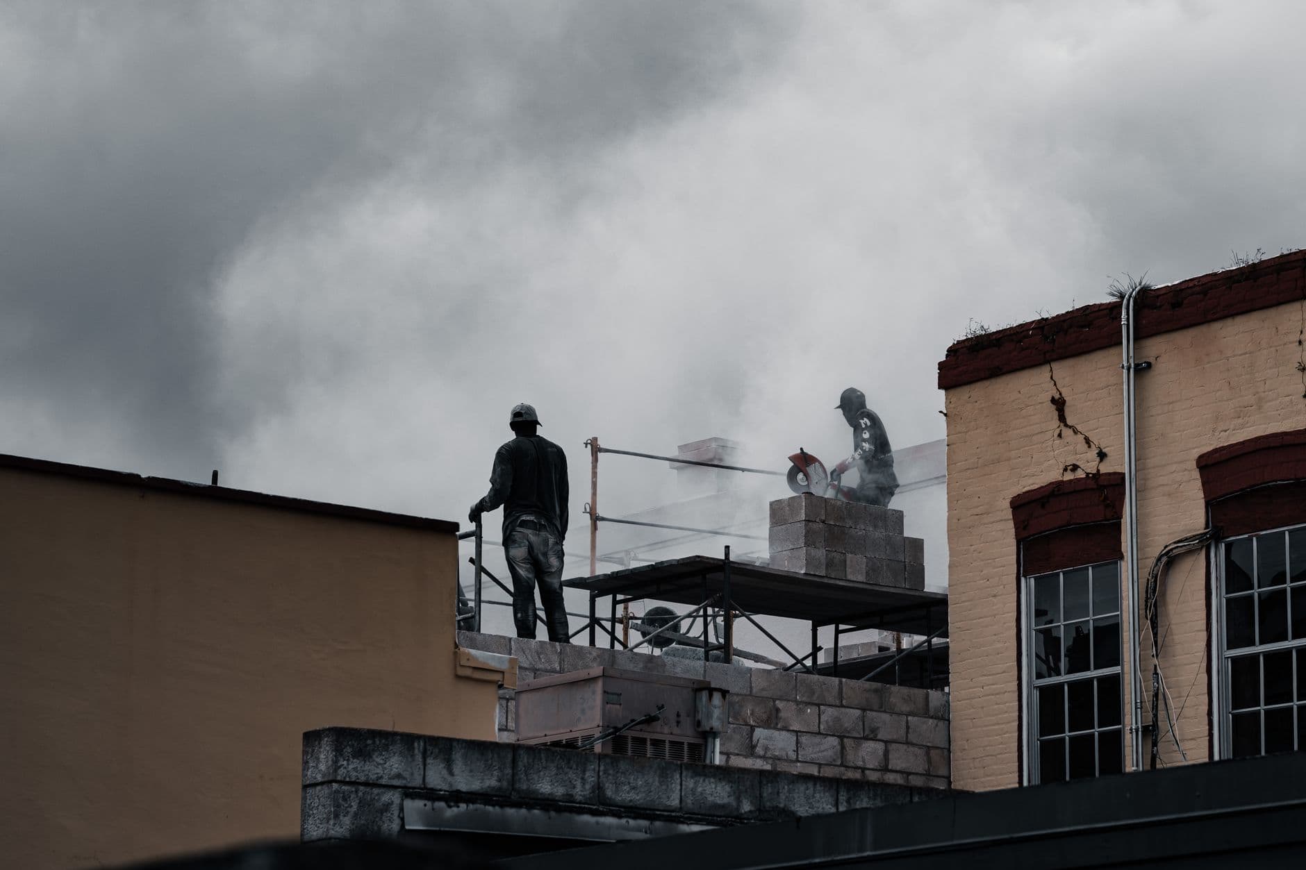 Website & Hosting for Contractors — Workers on a multi-storey building site using tools amidst a cloudy backdrop.