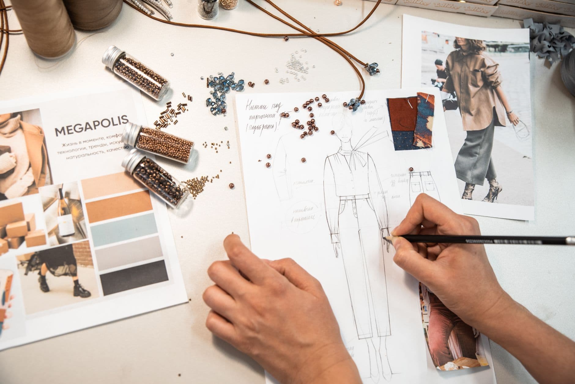 Branding — Fashion designer sketching in a workspace with materials and mood boards.