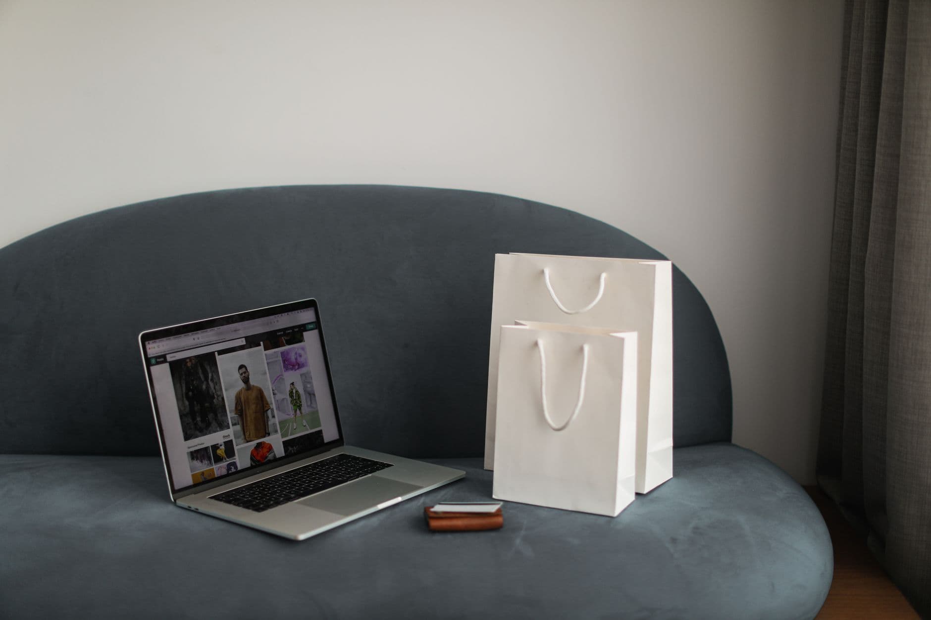 E-commerce Development — Online shopping setup with a laptop and shopping bags on a stylish couch.