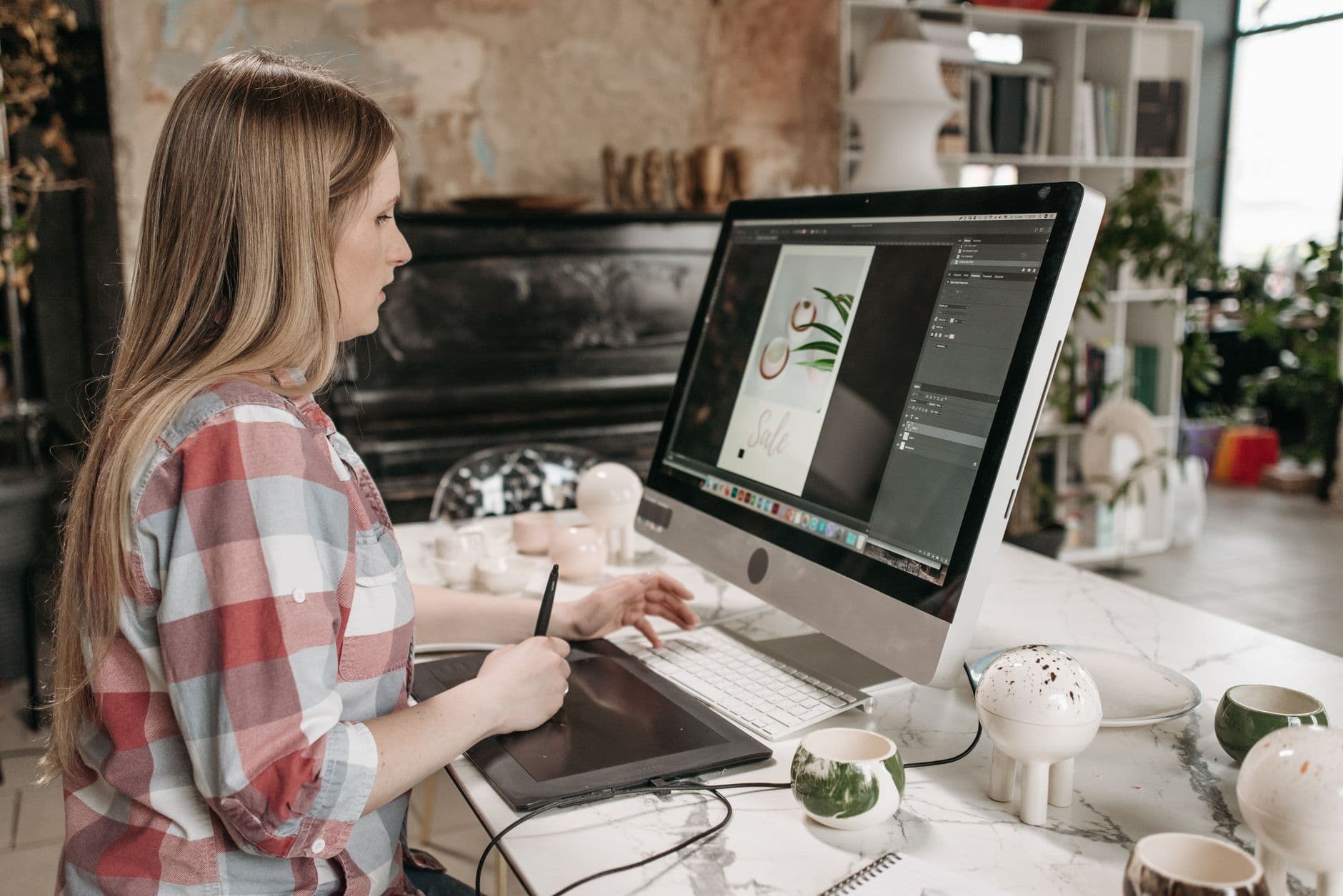 Graphic Design — Woman using a digital drawing tablet in a stylish office workspace, focused on graphic design.
