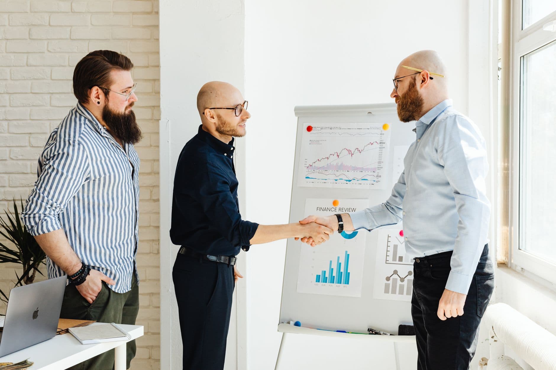 Lead Generation — Three business colleagues engage in a productive meeting, exchanging ideas with data charts.