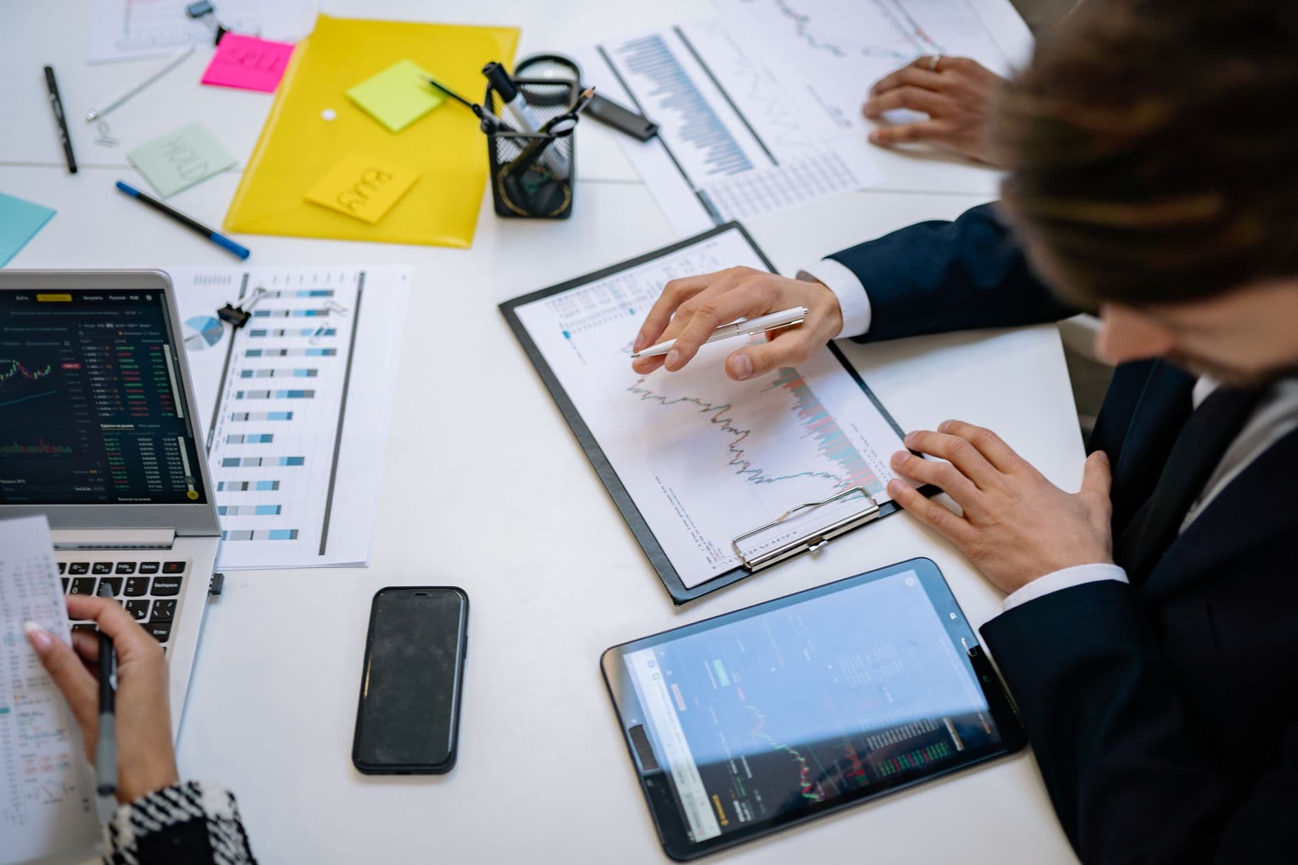 Marketing Automation — Team reviewing financial charts and digital data on tablets in an office setting.