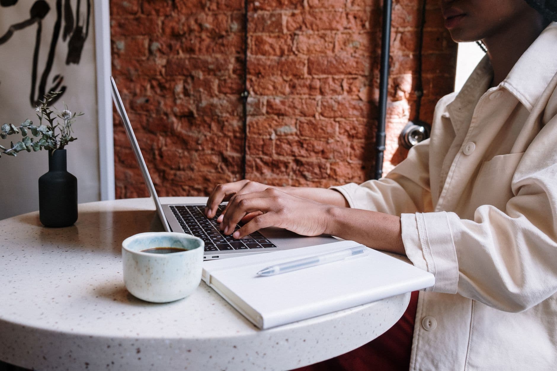 WordPress Hosting — Woman working on a laptop with coffee in a cozy café, highlighting a productive and modern vibe.