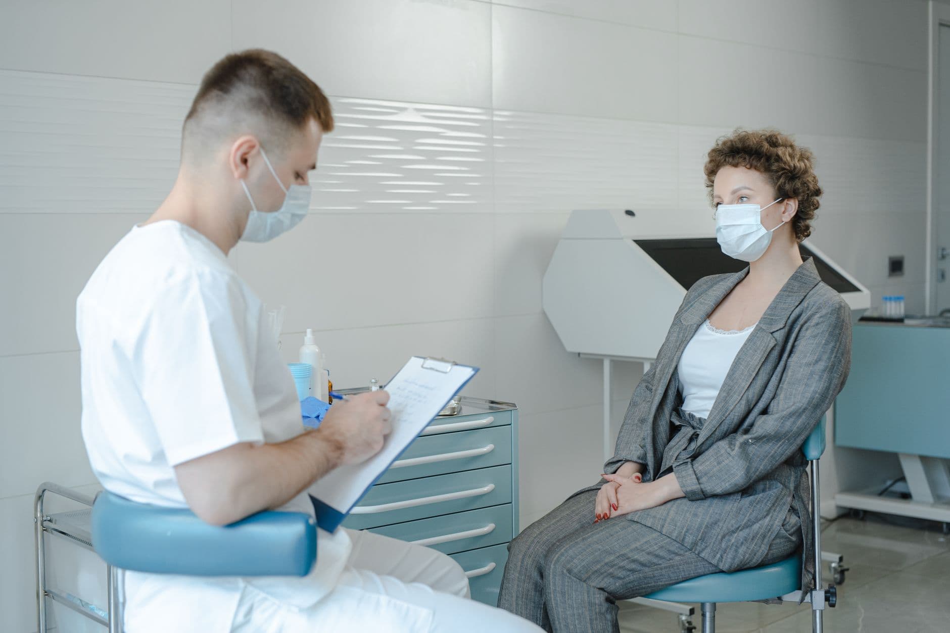 Website & Hosting for Doctors — A doctor in a face mask consults a patient in a clinic, reflecting the new normal.