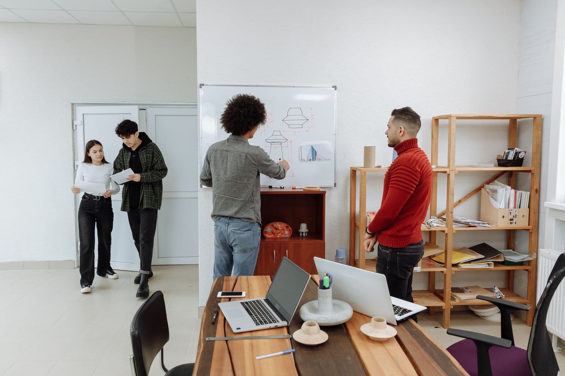 Website & Hosting for Startups — Diverse team collaborating in a modern office, discussing ideas with laptops and a whiteboard.