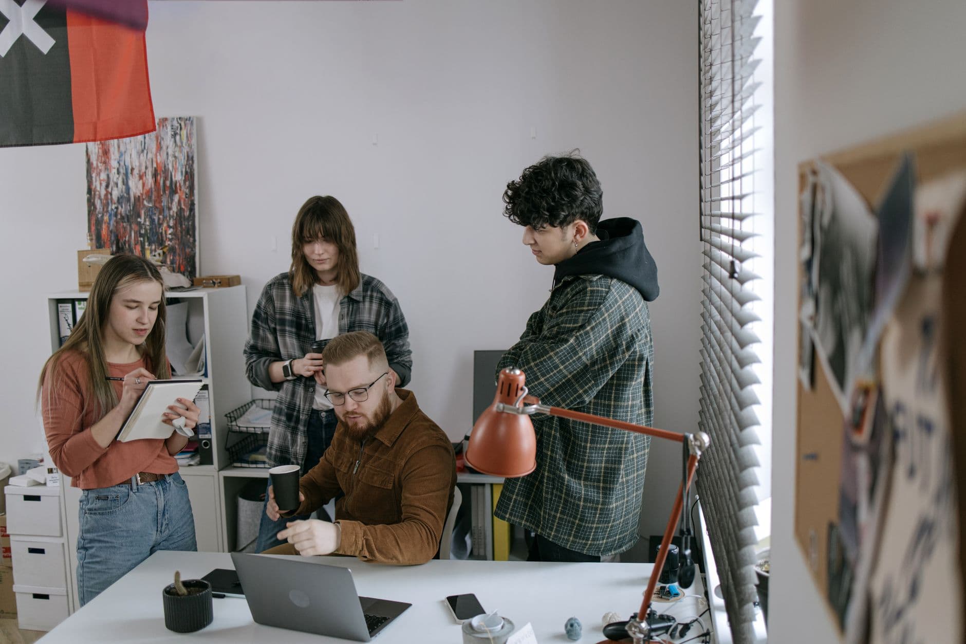 Website & Hosting for Startups — Group of young professionals having a team meeting around a laptop in a modern startup office.