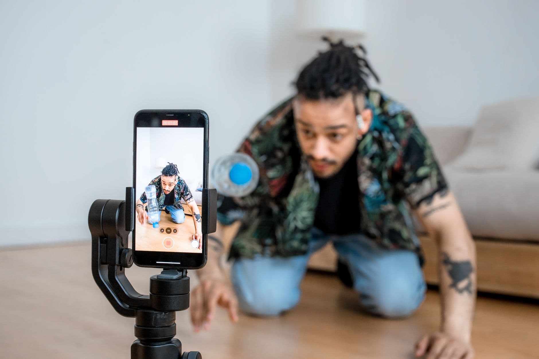 Social Media Management — Man filming creative content with smartphone on gimbal indoors.